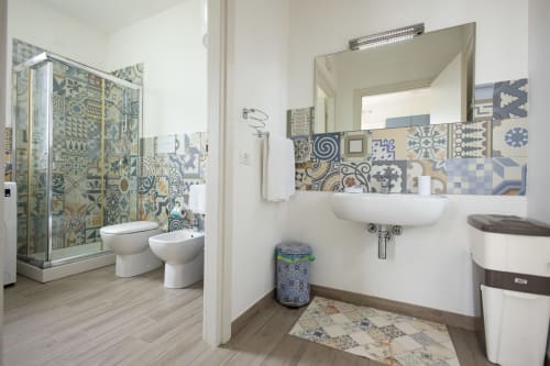 Modern bathroom at Senia del Rais in Favignana with patterned tile backsplash, white sink, toilet, and bidet