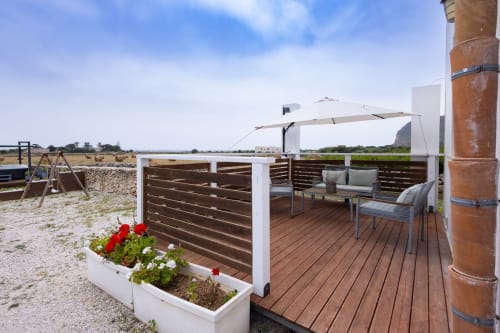 Outdoor terrace with lounge seating and umbrella at Senia del Rais in Favignana, overlooking countryside