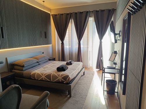 Camera moderna a Trastevere Noir Roma con letto matrimoniale, tende scure, accesso al balcone, TV a schermo piatto e arredamento contemporaneo