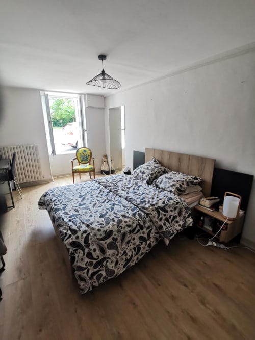 Chambre spacieuse à la Gite La Belle Hélène à Bressuire avec parure à motifs, lit en bois et vue sur le jardin
