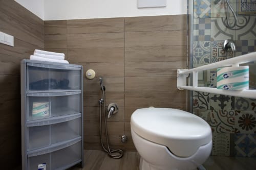 Modern bathroom in Senia del Rais apartment with toilet, shower enclosure, and storage shelving on wood-tiled walls