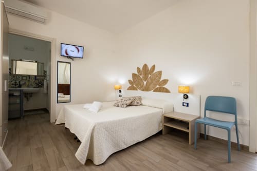 Modern bedroom in Tonno apartment at Senia del Rais B&B, Favignana, with white bed, wooden nightstands, and garden view