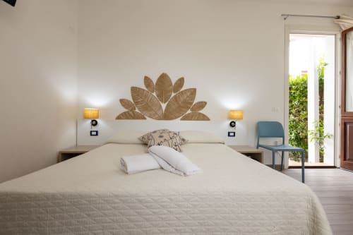 Modern bedroom at Senia del Rais in Favignana with queen bed, woven leaf headboard art, and garden view access