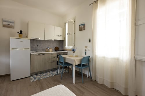 Modern kitchenette in Tonno apartment at Senia del Rais B&B, Favignana, with dining table and blue chairs