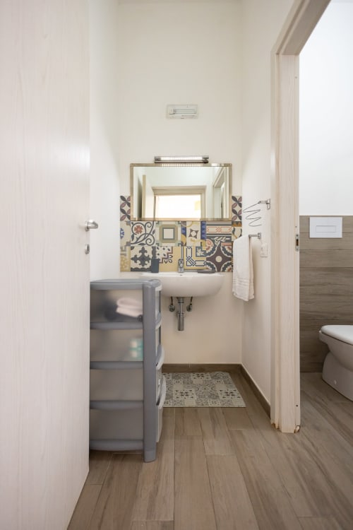 Modern bathroom in Tonno apartment at Senia del Rais, Favignana with sink, mirror, storage and decorative tile accents