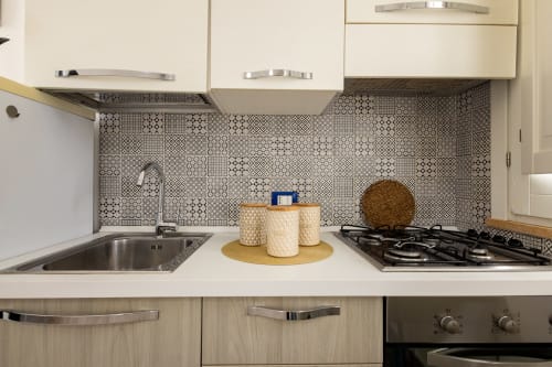 Modern kitchen in Senia del Rais apartment with patterned backtile, gas stove, sink, and white cabinetry in Favignana, Italy