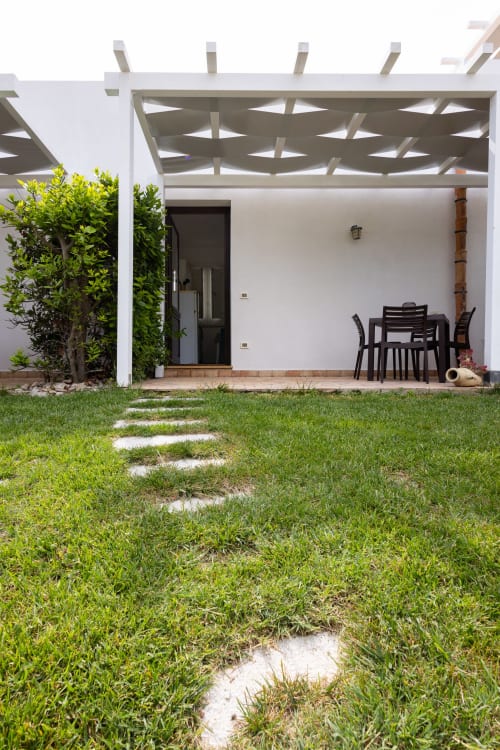 Modern garden terrace at Senia del Rais Favignana with dining setup, pergola, and manicured lawn