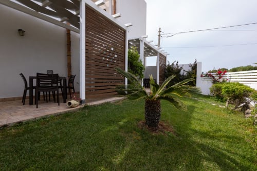 Garden view of Tonno apartment at Senia del Rais in Favignana with patio, dining table, palm tree, and outdoor seating