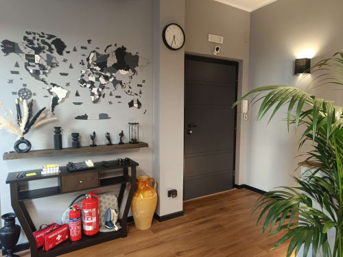 Ingresso moderno del Trastevere Noir B&B Roma con mappa del mondo, scrivania in legno, porta scura e pianta verde