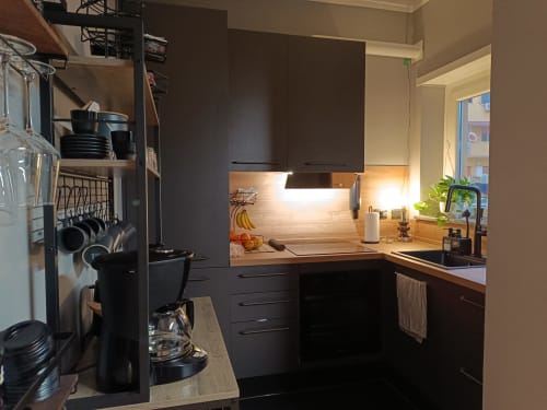 Cucina moderna nera con top in legno, illuminazione calda e vista sulla città presso Trastevere Noir B&B a Roma