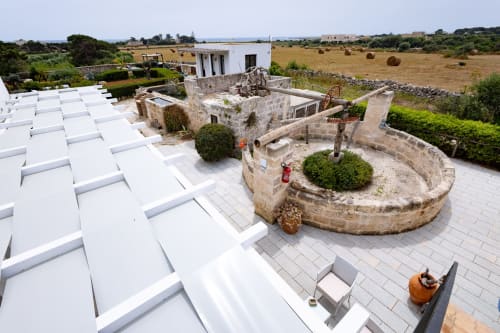 Aerial view of Senia del Rais B&B in Favignana showing stone courtyard, white accommodations, and sea views