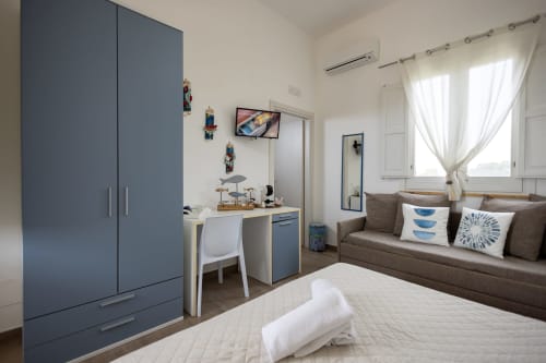 Corallo room at Senia del Rais in Favignana with bed, blue wardrobe, work desk, sofa and sea view