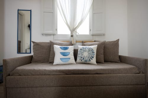 Cozy sea-view bedroom at Senia del Rais in Favignana with brown sofa, blue patterned pillows, and bright windows
