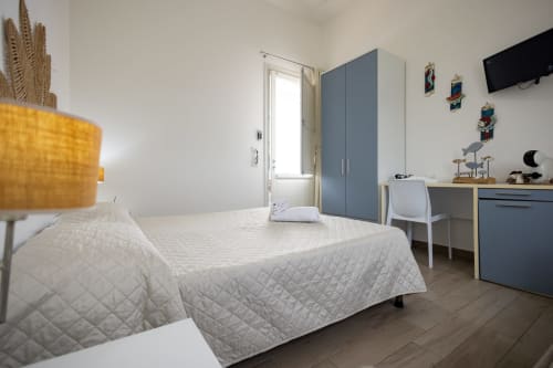 Bright bedroom at Senia del Rais B&B in Favignana with twin beds, blue wardrobe, work desk, and sea view window