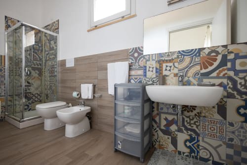 Modern bathroom in Corallo room at Senia del Rais B&B, Favignana with patterned tiles, white sink, and toilet