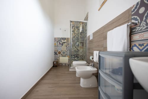 Modern bathroom with decorative patterned tiles, toilet, bidet, and wooden flooring at Senia del Rais B&B in Favignana