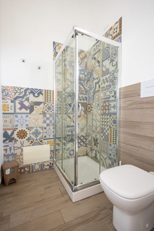 Modern bathroom at Senia del Rais, Favignana featuring colorful patterned tile shower enclosure and white toilet