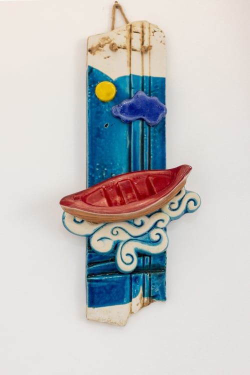 Handcrafted wooden nautical wall decoration with red boat, blue waves, sun and cloud at Senia del Rais in Favignana