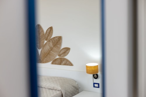 Modern hotel room at Senia del Rais in Favignana with minimalist decor, wall art, bed, and bedside lamp