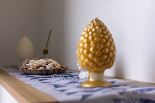 Decorative gold pinecone and shells on blue patterned table at Senia del Rais, Favignana apartment