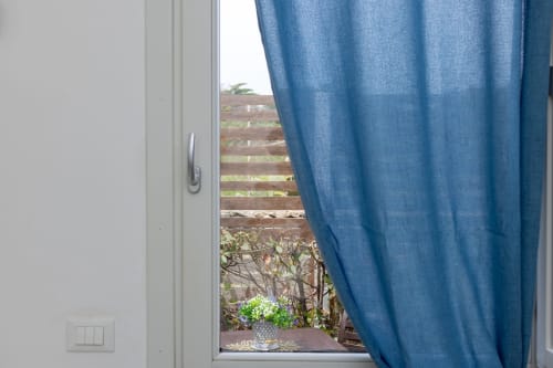 Open glass door with blue curtain overlooking mountain terrace at Senia del Rais in Favignana