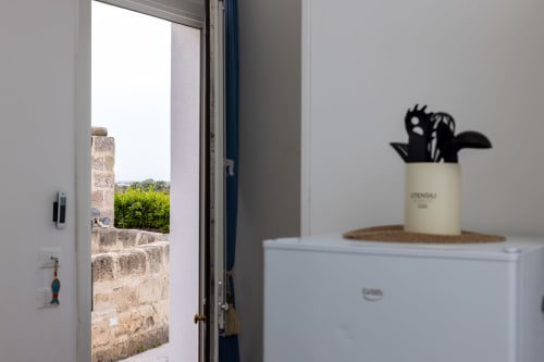 Modern apartment interior at Senia del Rais, Favignana, with open door overlooking stone walls and garden view