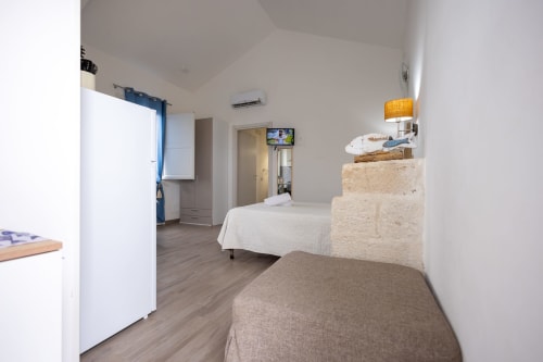 Sardina apartment bedroom at Senia del Rais in Favignana with beds, TV, refrigerator, and air conditioning