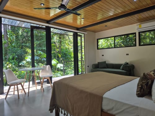 Habitación Morpho en Fauna Lodge con cama, balcón con vista al bosque, sala de estar, ventilador de techo y vistas del dosel verde en Costa Rica