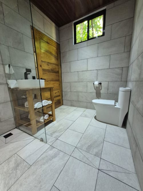 Baño moderno en Fauna Lodge con ducha abierta, tocador de madera y piso de cerámica en Península de Osa, Costa Rica