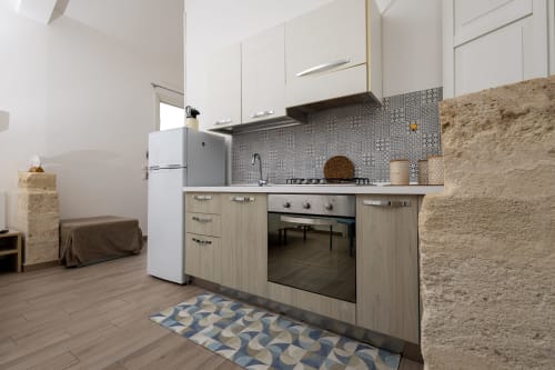 Modern kitchen in Sardina apartment at Senia del Rais, Favignana, with white cabinets, geometric backtile, and stainless