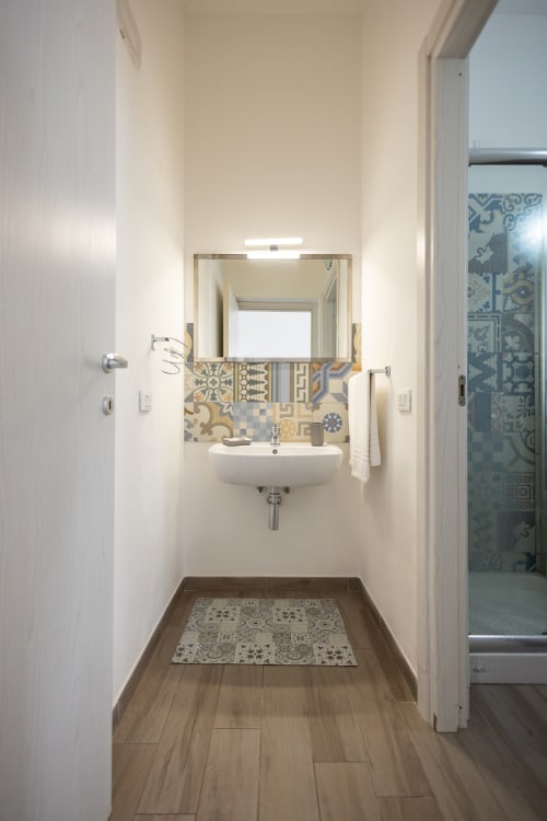 Modern bathroom at Senia del Rais in Favignana with sink, mirror, patterned tiles, wooden floors