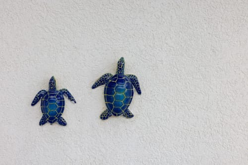 Two blue sea turtle decorations on white wall at Tartaruga Marina room, Senia del Rais in Favignana