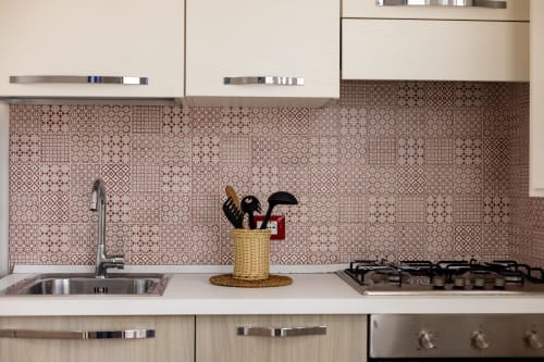Modern kitchen with patterned backtile, sink, gas cooktop, and utensil holder at Senia del Rais apartment in Favignana.