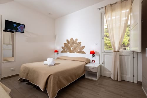 Bright bedroom in Tartaruga Marina apartment at Senia del Rais, Favignana with beige bedding, leaf wall art, and ocean view
