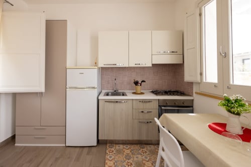 Compact kitchen in Tartaruga Marina apartment at Senia del Rais, Favignana with stove, sink, refrigerator and wooden