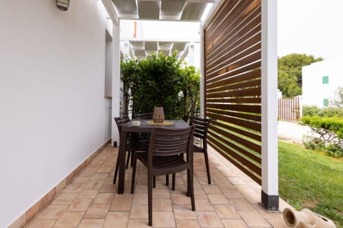 Outdoor dining area at Senia del Rais, Favignana with dark table, chairs, pergola and wooden privacy screen overlooking