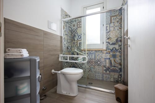 Modern bathroom in Tartaruga Marina apartment at Senia del Rais, Favignana, featuring patterned tile shower enclosure, white