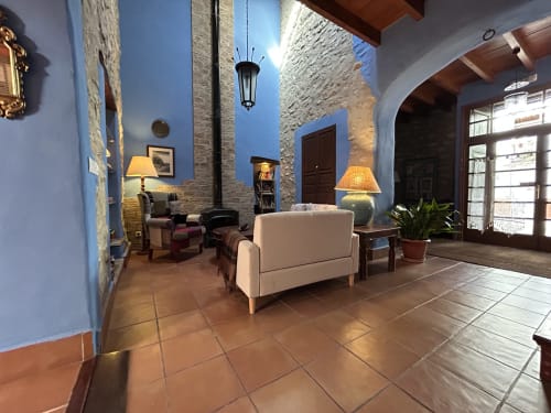 Elegant courtyard at Casa Gallinera boutique vacation home in Alicante featuring blue walls, terracotta tiles, and rustic stone