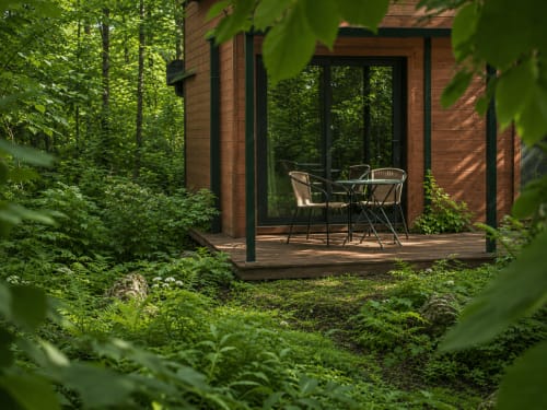Modern brick cabin with patio seating nestled in lush forest at Les Lodges de Vaugrigneuse, Vaugrigneuse