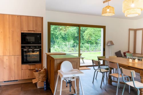 Cuisine moderne et salle à manger avec armoires en bois et grandes fenêtres donnant sur les jardins de la villa Château de la Malmaison