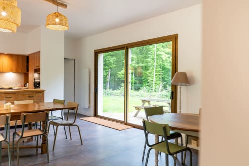 Séjour lumineux et moderne avec mobilier en bois, grandes portes vitrées ouvertes sur le jardin du Château de la Malmaison