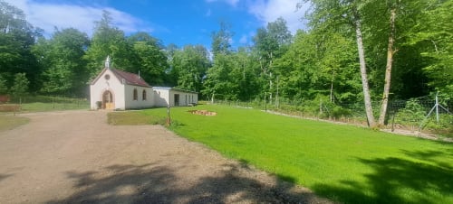 Chapelle blanche historique à la Malmaison en Champagne, entourée de pelouses vertes et de forêts.