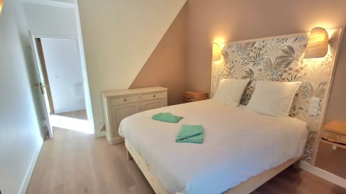 Chambre mansardée élégante au Château De La Malmaison avec lit queen-size, tête de lit motifs, luminosité chaleureuse et parquet