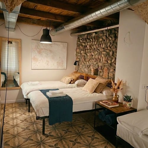 Camera moderna all'Apartments Borgovivobg Bergamo con due letti, parete in mattoni a vista e dettagli industriali al soffitto