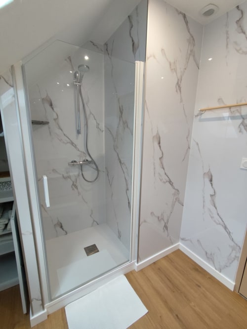 Douche moderne avec parois effet marbre à l'hôtel Accolade à Châteaudun, France
