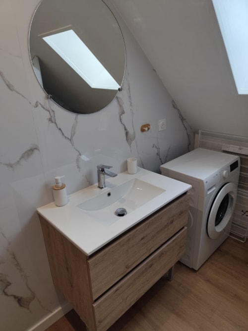 Salle de bains moderne avec miroir ovale et machine à laver à l'hôtel Accolade, Châteaudun