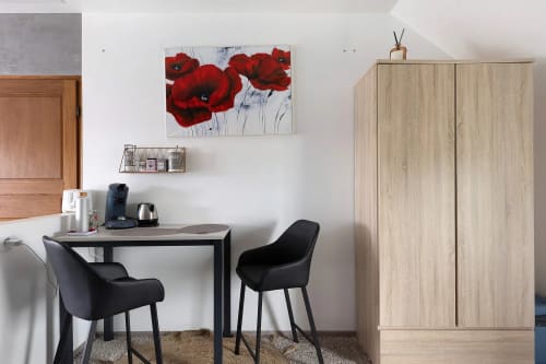 Espace de travail moderne à Le Petit Villeneuve avec bureau noir, chaises, œuvre coquelicot rouge et armoire en bois clair