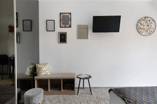 Chambre moderne au Petit Villeneuve avec TV murale, tableaux encadrés, banquette, horloge ronde et jardin