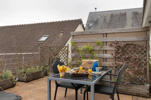 Terrasse sur le toit du Petit Villeneuve avec table de petit-déjeuner, vue sur le jardin et clôture à treillis à Saint-Georges-sur-Cher