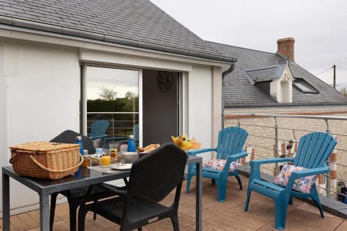 Terrasse du gîte Le Petit Villeneuve à Saint-Georges-sur-Cher avec chaises Adirondack bleues et vue sur le jardin